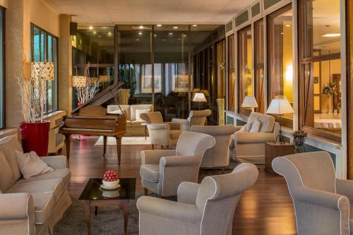 a living room with couches and a piano at Hotel Ambasciatori in Brescia