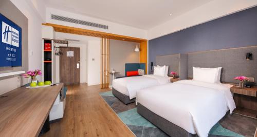a hotel room with two beds and a desk at Holiday Inn Express Chengdu East Railway by lHG - Near The World Games Gymnasium in Chengdu