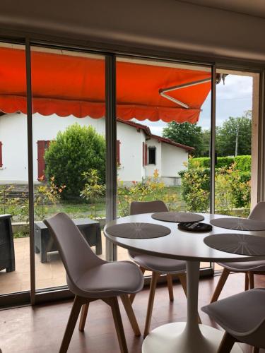 une table et des chaises dans une pièce avec une grande fenêtre dans l'établissement Appartement cosy, en rez de chaussée, en plein centre de CAmbo les Bains, à Cambo-les-Bains