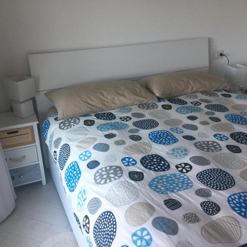 a bed with a blue and white comforter on it at Carrabean sea in the North of Sardegna, with swimming pool in Viddalba