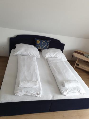 een bed met witte lakens en kussens erop bij Gesztenye apartman in Úrkút