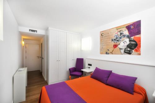 a bedroom with an orange and purple bed and a desk at Hospedium CLÁ Hotel - Boutique in Teruel