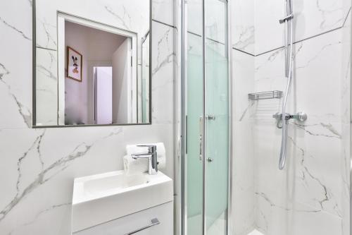 une salle de bain blanche avec un lavabo et une douche dans l'établissement 72 - Mermoz Mickey Mouse, à Paris