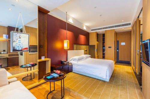 a hotel room with a bed and a tv at Hotel Kapok Shenzhen Bay in Shenzhen