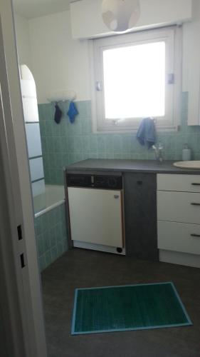 uma cozinha com um fogão, um lavatório e uma janela em Les Trinitaires em Sarzeau