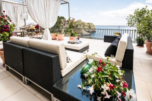 a patio with a couch and tables and flowers at 202 luxury terrace view in Taormina