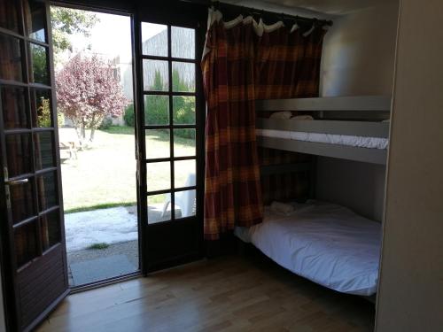 Zimmer mit einem Etagenbett und einer Tür mit einem Fenster in der Unterkunft Appartement avec Terrasse in Saint-Aubin-sur-Mer