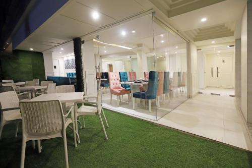 斋浦尔Hotel Magenta Jaipur的餐厅设有桌椅和玻璃墙