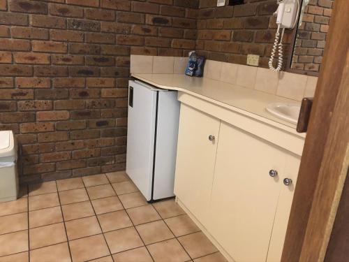 a bathroom with a sink and a white refrigerator at Travellers Rest Motor Inn Swan Hill in Swan Hill