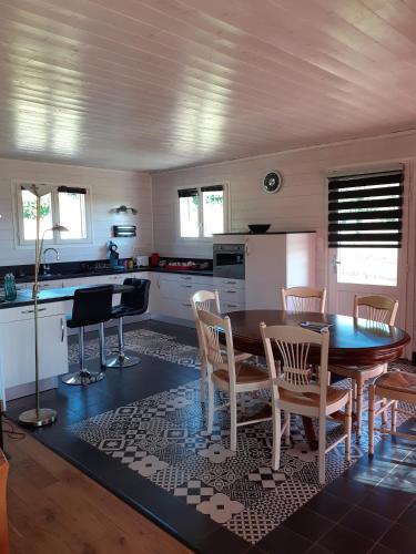 une cuisine avec une table et des chaises et une cuisine avec des placards blancs dans l'établissement PETITE MAISON EN BOIS, à Rogues