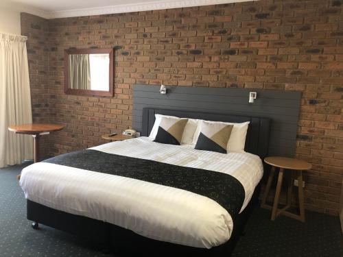 a bedroom with a large bed and a brick wall at Travellers Rest Motor Inn Swan Hill in Swan Hill