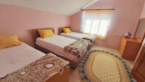 1 dormitorio con 2 camas, ventana y silla en Guest House Pogradeci en Pogradec