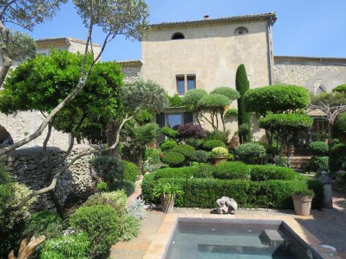 un jardin avec une piscine en face d'un bâtiment dans l'établissement Les Buis de Lussan, à Lussan