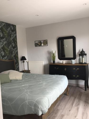 a bedroom with a bed and a dresser with a tv at Côté jardin des Charmilles in Quettehou