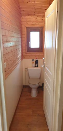 a bathroom with a white toilet in a wooden room at Chalets les Silènes in Doucier