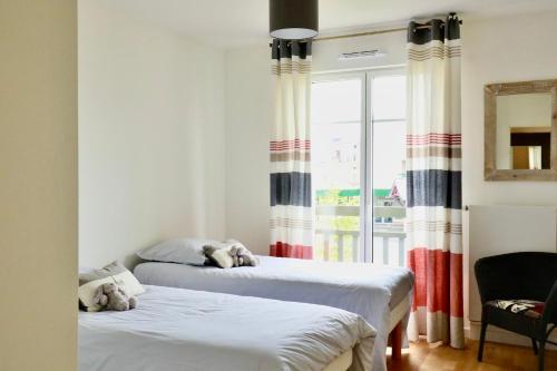 two beds in a room with a window at Appartement des Arts in Deauville