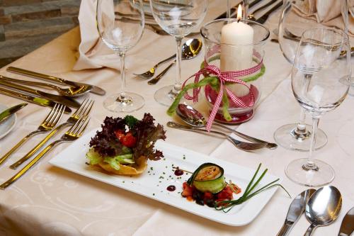 a table with a plate of food and wine glasses at Wohlfühlhotel Berg Heil in Holzgau