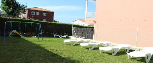 a park with white chairs and a playground at Apartamentos baltar sanxenxo 1 in Sanxenxo