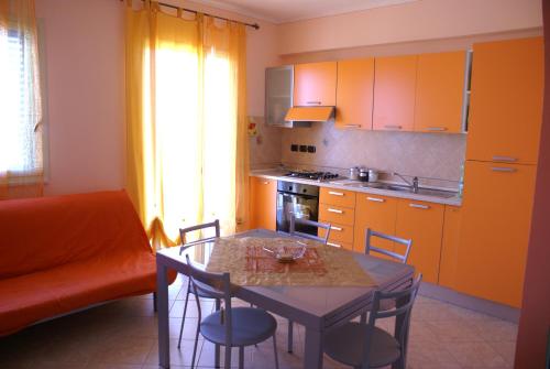 une cuisine avec une table et des chaises et une cuisine avec des armoires orange dans l'établissement Appartamento Torre, à Finale