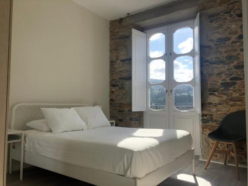 a bedroom with a white bed and a window at Noray Apartamentos Viveiro in Viveiro