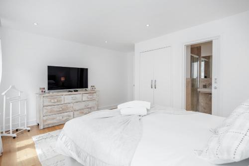 a white bedroom with a bed and a tv at The white home near Kensington high st in London