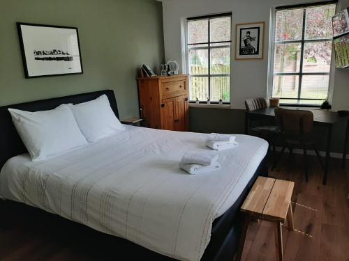 B&B De Reede في أورك: غرفة نوم بسرير وطاولة ونوافذ