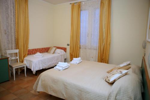 里米尼的住宿－拉拖雷酒店，一间卧室设有两张床、一把椅子和一个窗户。