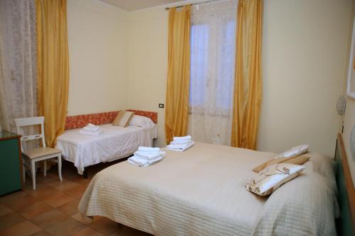 a bedroom with two beds and a chair and a window at Hotel La Torre in Rimini