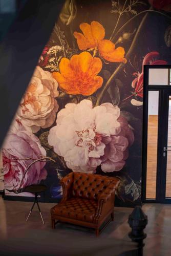 a painting of flowers on a wall next to a chair at Schlosshotel Braunfels & Himmelreich in Braunfels