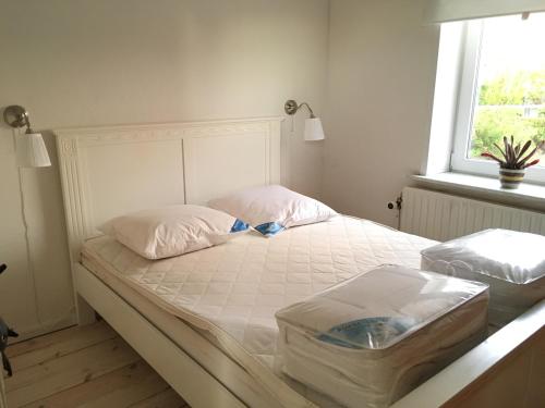 Schlafzimmer mit einem großen weißen Bett und einem Fenster in der Unterkunft Herlebo in Tønder