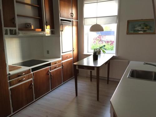 a kitchen with wooden cabinets and a table in it at Herlebo in Tønder
