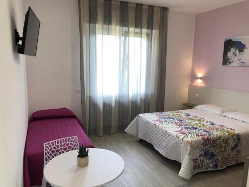 a bedroom with a bed and a table and a window at Nel Conero Affittacamere in Numana