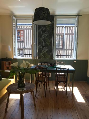 un salon avec une table, des chaises et des fenêtres dans l'établissement AU NAIN ROUGE gite vintage de charme, à Cormeilles