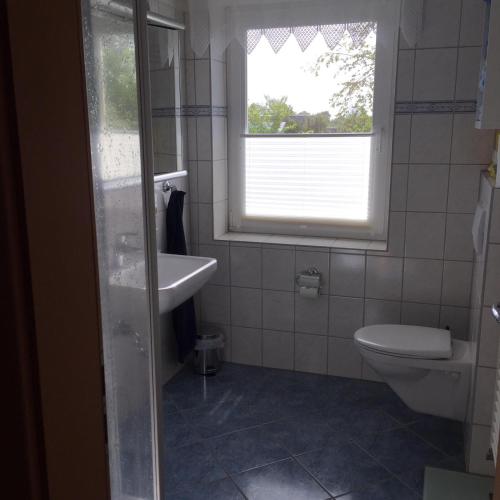 a bathroom with a toilet and a sink and a window at Ferienhaushälfte Domeyer Midlum in Midlum