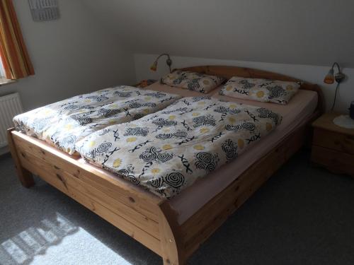 1 cama con marco de madera y edredón azul y blanco en Ferienhaushälfte Domeyer Midlum, en Midlum