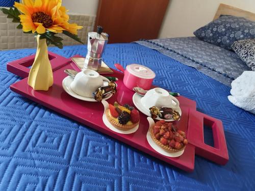 uma bandeja com comida de pequeno almoço numa cama com uma flor em B&B Cappotto civico 48 em Pompeia
