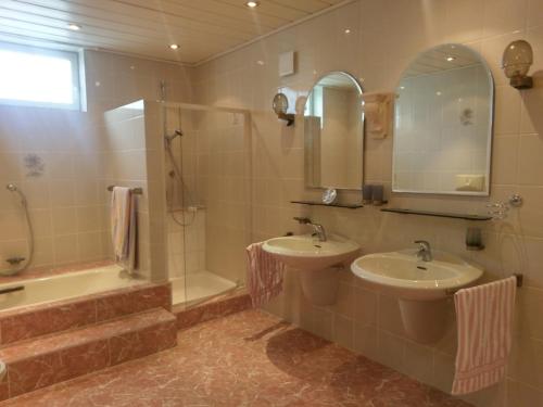 łazienka z 2 umywalkami, prysznicem i wanną w obiekcie Ferienwohnung Wolf w mieście Tittling