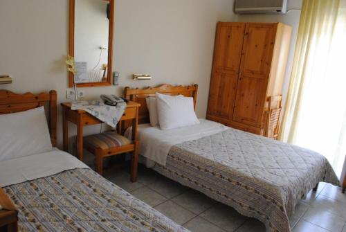 une chambre avec deux lits, un bureau et un miroir dans l'établissement Pyrassos, à Nea Anchialos