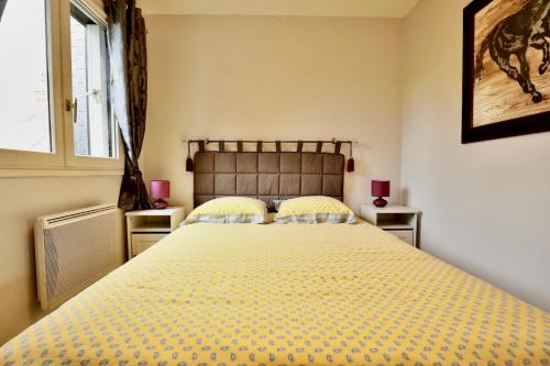 a bedroom with a large bed with yellow sheets and a window at Le Yearling in Deauville