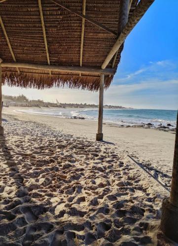 a straw umbrella on a beach with the ocean at Chalés Amarante in Fortim