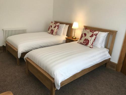 two twin beds in a room with a lamp at Scarborough House - Adults only holiday home in Torquay