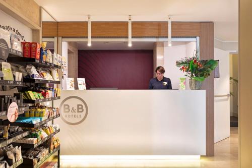 a woman standing behind a counter in a store at B&B Hotel Milano Sant'Ambrogio in Milan