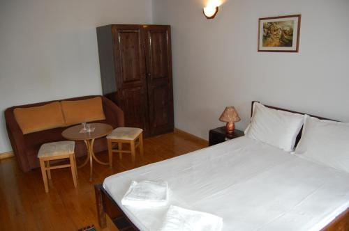 a bedroom with a bed and a chair and a table at Kazasovata Guest House in Tryavna