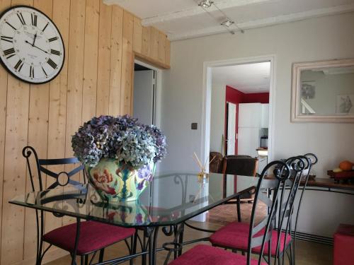 un vase de fleurs sur une table en verre avec des chaises dans l'établissement Le tulipier, à Manneville-la-Raoult