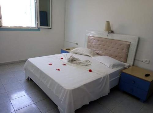 a bedroom with a white bed with red roses on it at Houria House Sable D'or in Mahdia