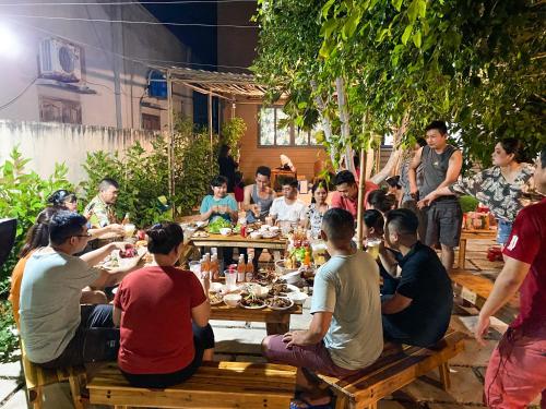 Lala Chill Homestay في كي جا: مجموعة من الناس يجلسون حول طاولة يأكلون الطعام