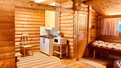 a kitchen in a log cabin with a refrigerator and a microwave at Urpolan Kartano Ky in Humppila