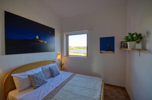 a bedroom with a bed and a window at Porto Coda Cavallo - Salina Bamba in San Teodoro