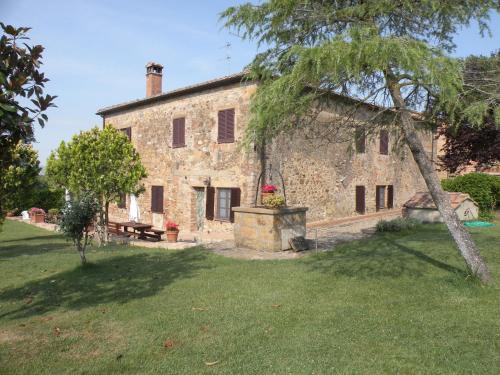 an old stone house with a tree in the yard at Agriturismo Casalpiano in Pienza