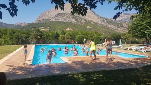a group of people in a swimming pool with a mountain in the background at Camping Oliana in Oliana